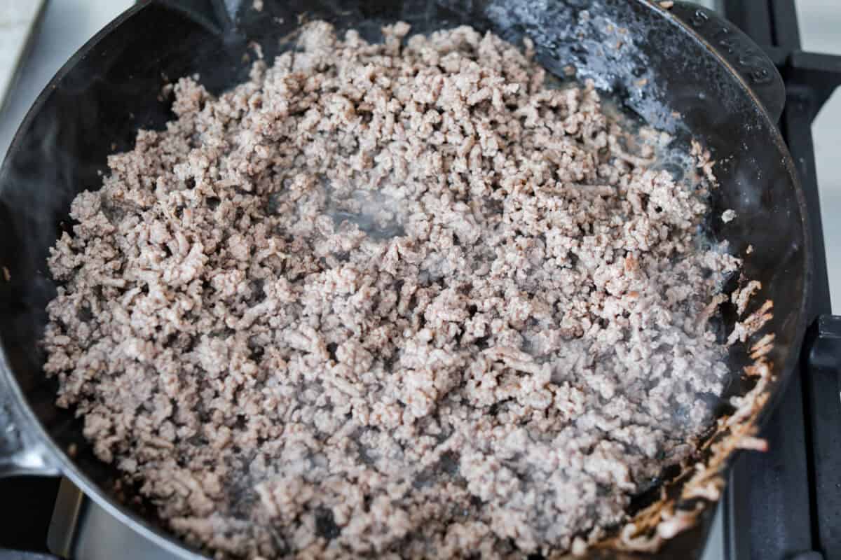 Overhead shot of beef being browned in a skillet. 