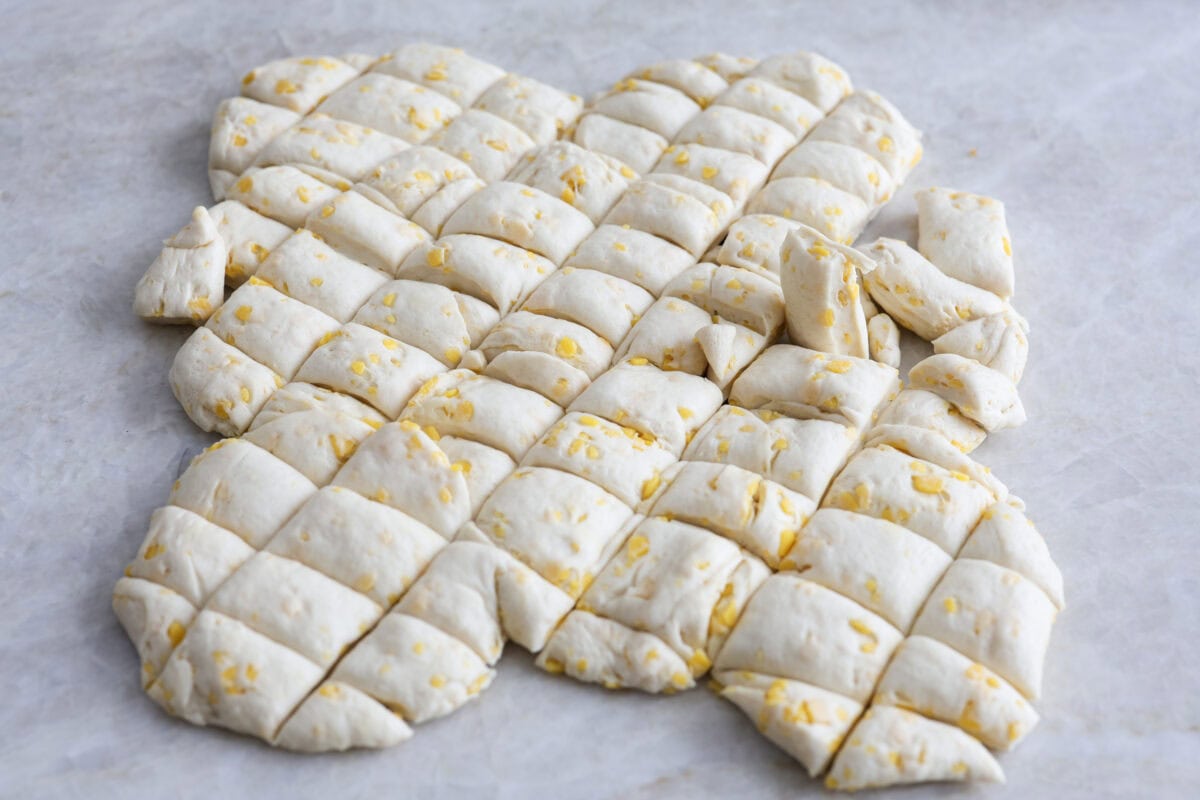 Angle shot of rolled biscuit dough that has been cut into one inch cubes.