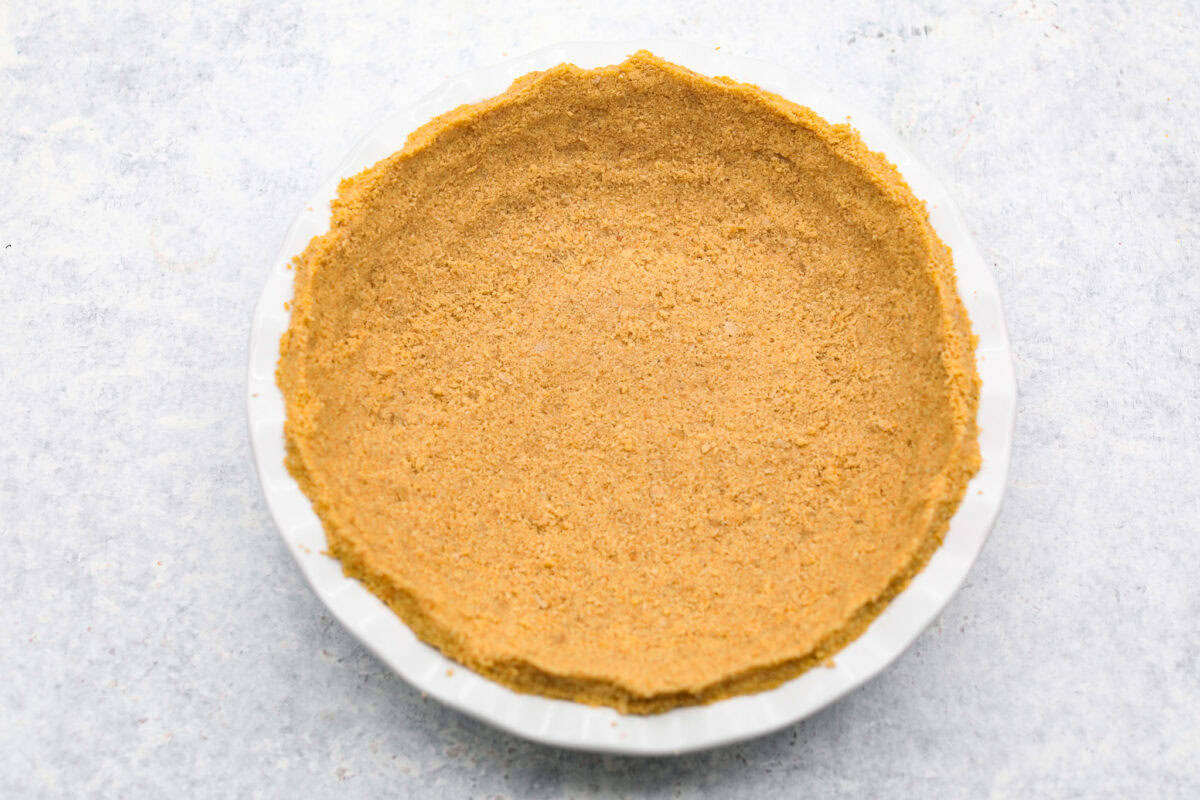 Overhead shot of crust ingredients smashed into a crust shape in a pie pan. 