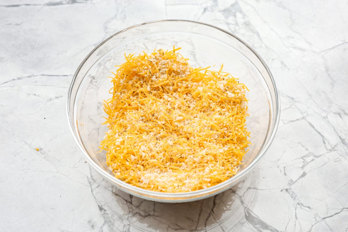 Overhead shot of cheese, breadcrumbs salt pepper and herbs mixed together in a bowl. 