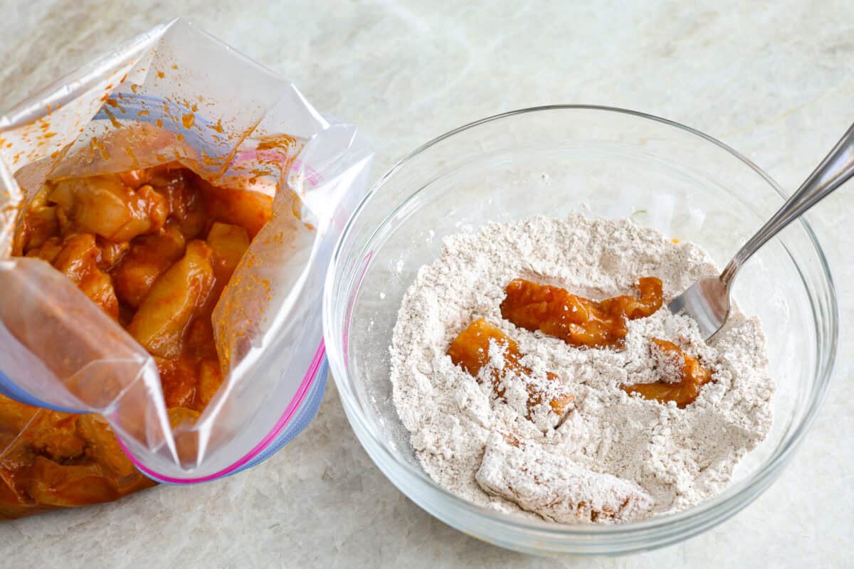 Overhead shot of marinated dragon chicken being coated in breading mixture. 