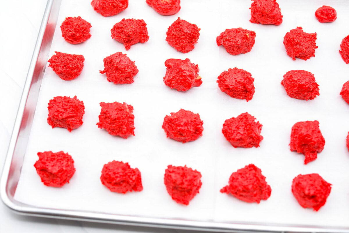 Overhead shot of Oreo grinch balls of filling on a parchment lines cookie sheet. 