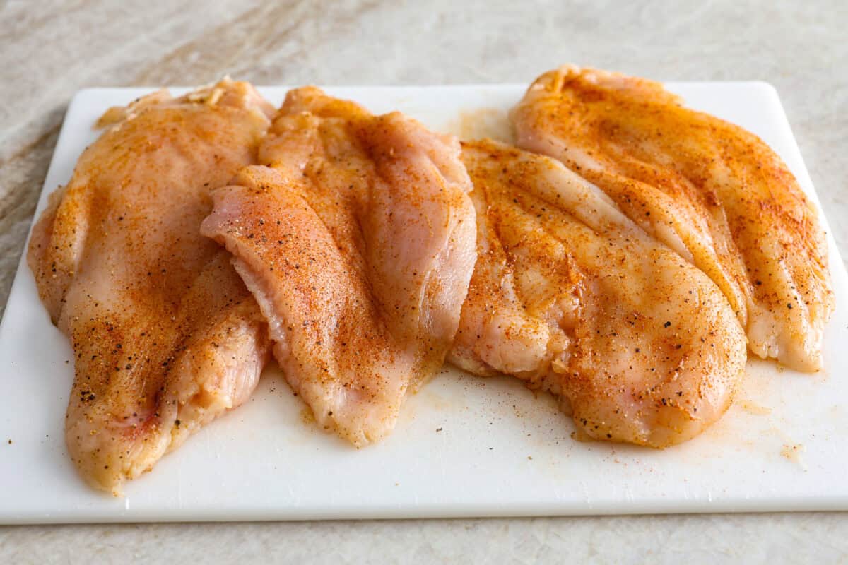 Overhead shot of seasoned chicken breasts on a cutting board. 