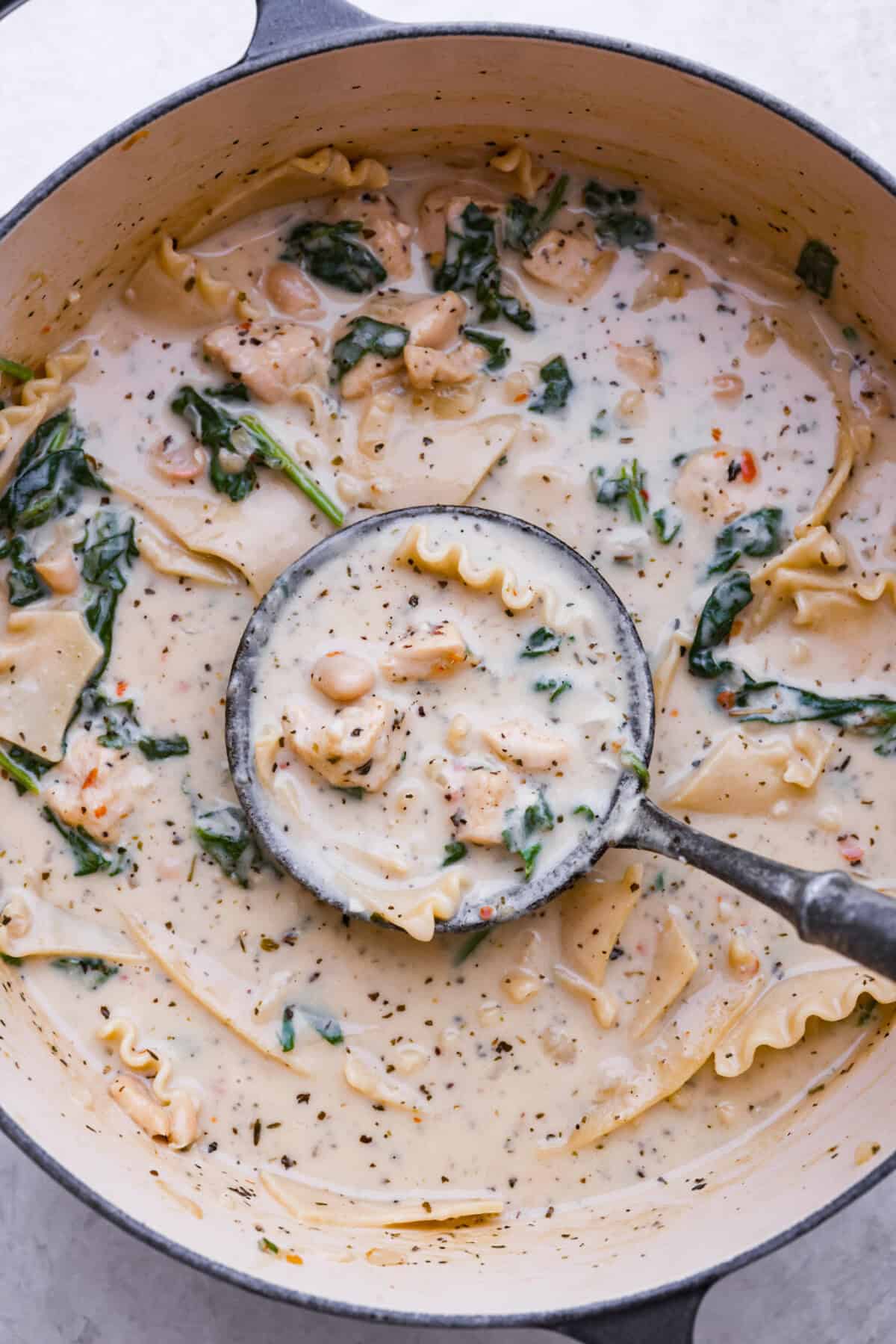 Overhead shot of white lasagna soup in a pot with a ladle. 