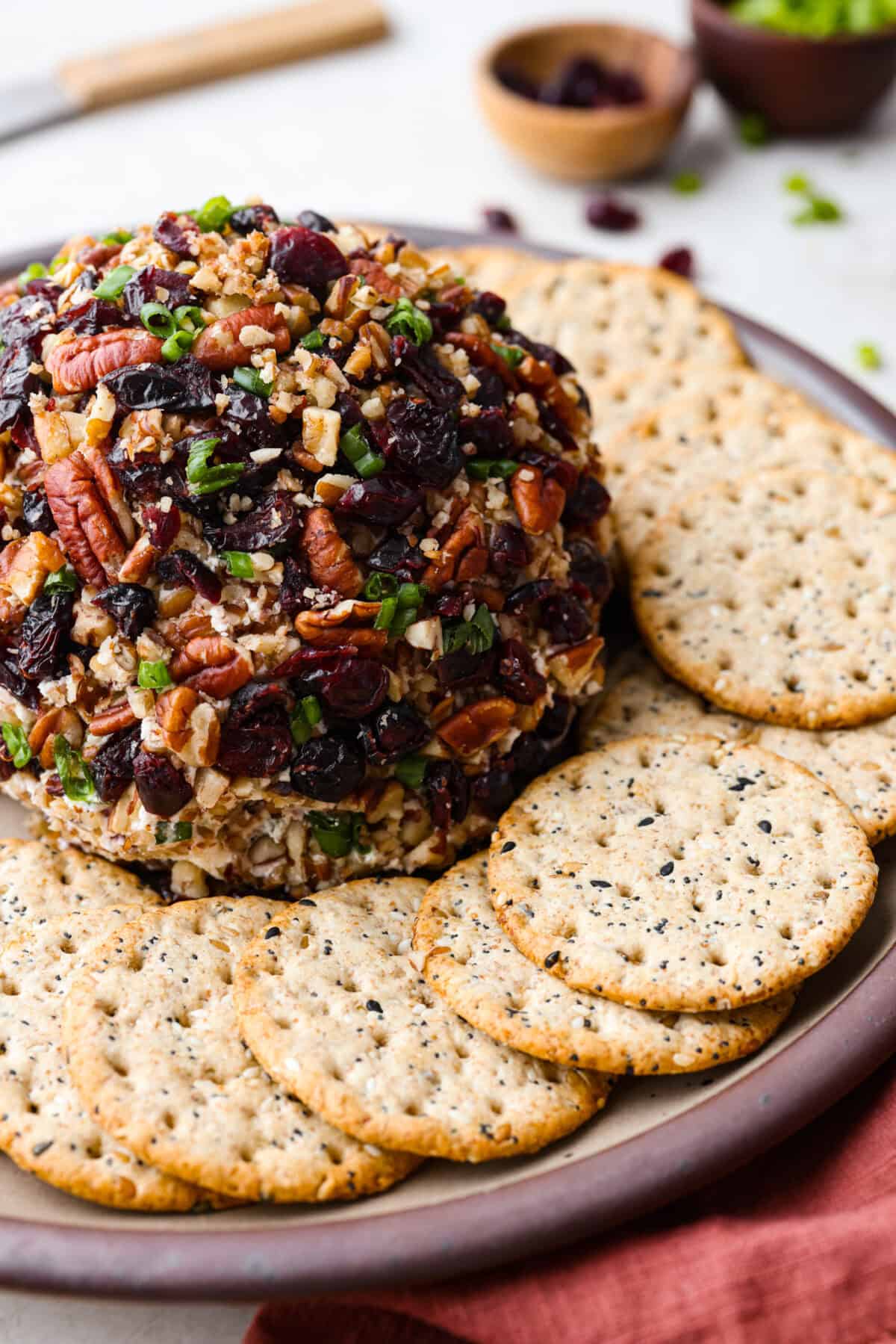 Close view of the cranberry pecan cheese ball on a platter surrounded by crackers.