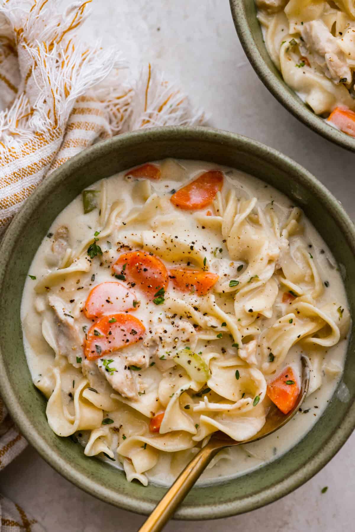 This creamy chicken noodle soup tastes exactly how it sounds! It's classic chicken noodle soup but creamy, rich and filling! Loaded with hearty chicken, tender carrots, supple noodles, and lots of delicious flavors, it's perfect for winter! Overhead shot of a bowl of creamy chicken noodle soup.