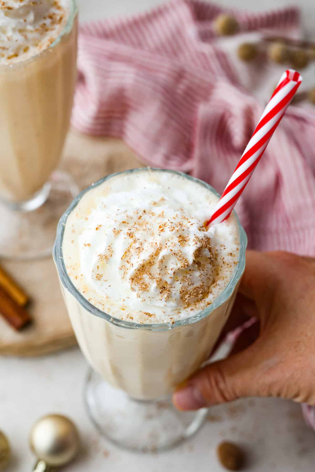 This creamy Eggnog Milkshake is decadent and super flavorful. It takes four simple ingredients and 5 minutes of your time. If you thought you liked eggnog before, you are going to absolutely love it after trying this shake. Overhead shot of eggnog milkshake with whipped cream and fresh nutmeg shavings on top.