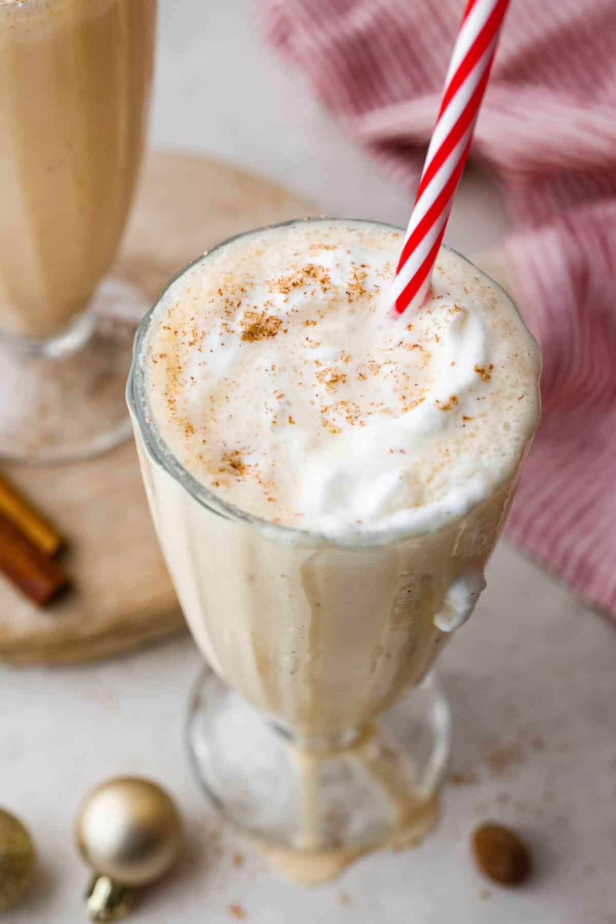 This creamy Eggnog Milkshake is decadent and super flavorful. It takes four simple ingredients and 5 minutes of your time. If you thought you liked eggnog before, you are going to absolutely love it after trying this shake. Angle shot of eggnog milkshake dripping down the sides of the glass.