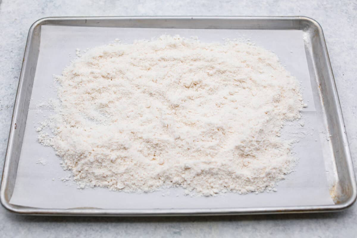 Overhead shot of cake mix spread out on a baking sheet to be heat-treated. 