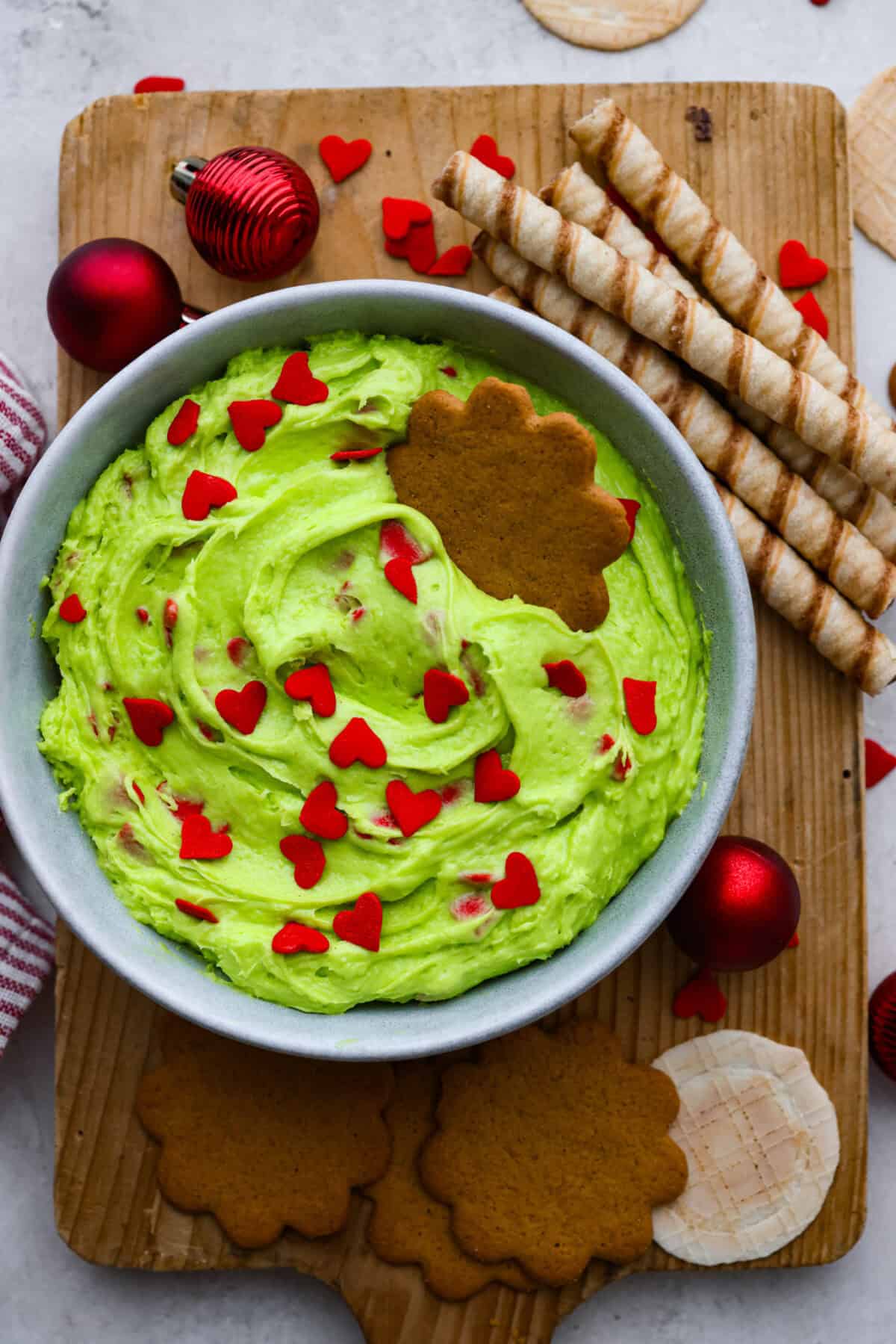 Overhead shot of grinch dip in a bowl surrounded by cookies and Christmas items. 