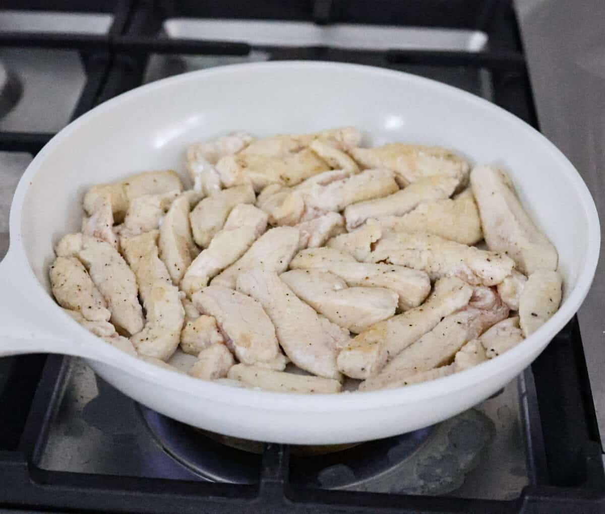 Hunan chicken is a tasty take-out favorite that can be made right at home! Tender chicken and veggies are tossed in the signature hunan sauce. It's savory with a hint of sweet and spicy! This easy one-pan dinner is ready in 30 minutes! Second photo of the chicken browning in the skillet.