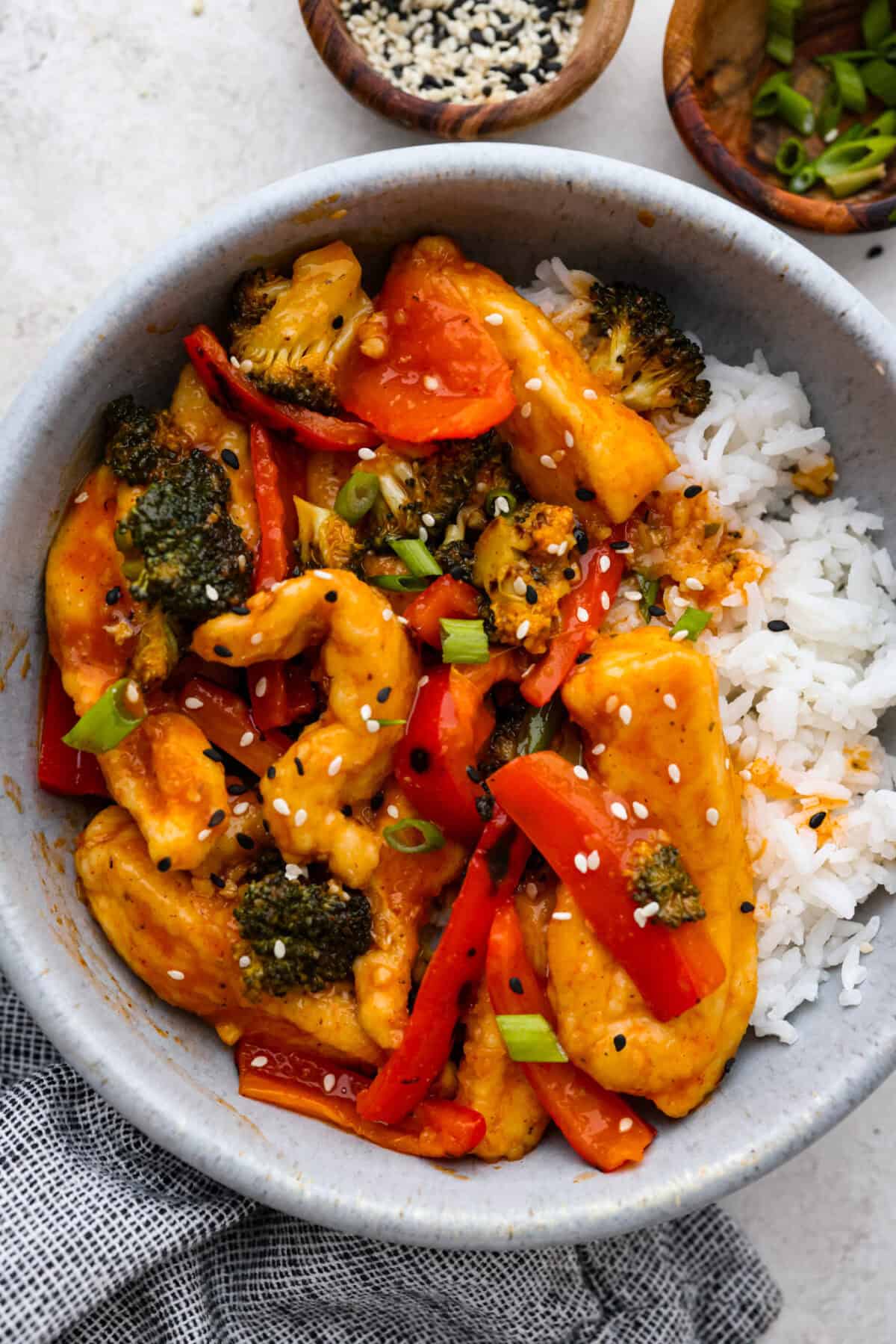 Hunan chicken is a tasty take-out favorite that can be made right at home! Tender chicken and veggies are tossed in the signature hunan sauce. It's savory with a hint of sweet and spicy! This easy one-pan dinner is ready in 30 minutes! Close view of Hunan chicken in a bowl with rice.