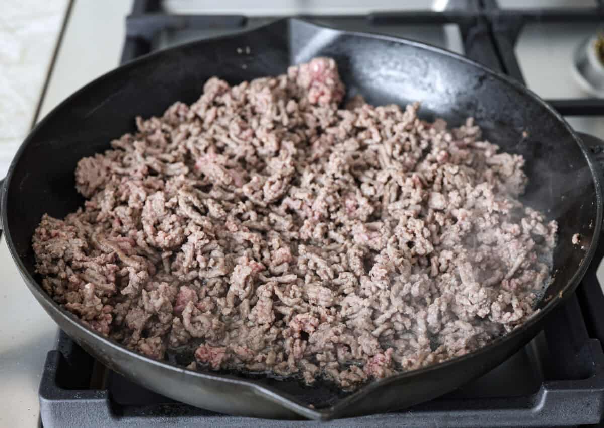 Angle shot of ground beef browning in a skillet. 