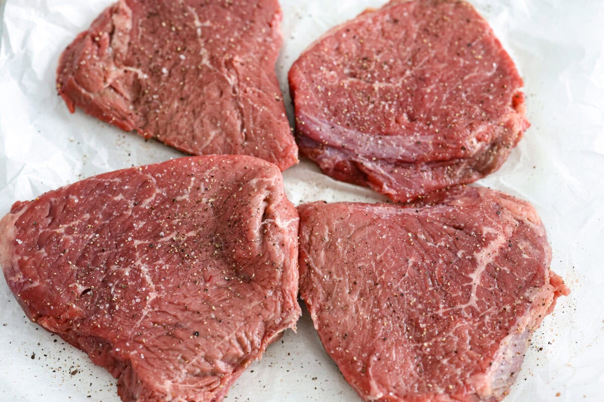 Craving Southern comfort food? This smothered steak is hearty, flavorful, and so satisfying. Perfectly cooked tender steak is covered in a rich, savory gravy that takes it to the next level. This steak is ready to enjoy in just 30 minutes! Overhead shot of seasoned steaks.