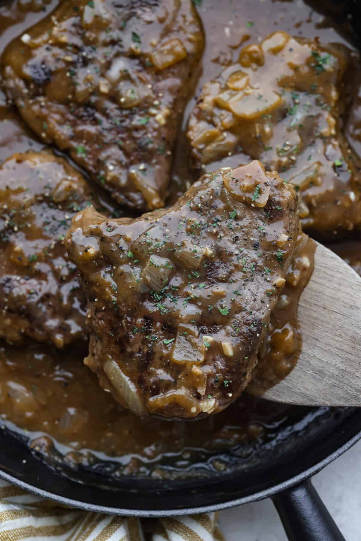 Craving Southern comfort food? This smothered steak is hearty, flavorful, and so satisfying. Perfectly cooked tender steak is covered in a rich, savory gravy that takes it to the next level. This steak is ready to enjoy in just 30 minutes! Close up shot of smothered steak.