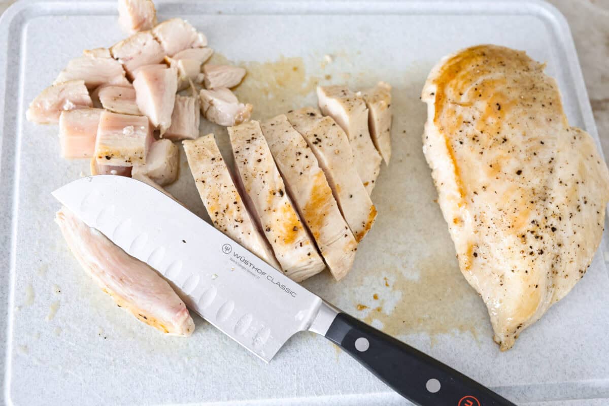 Chicken a la king is a timeless recipe that’s perfect for cozy dinners! This classic dish features tender chicken and veggies in a rich, creamy gravy-like sauce loaded with savory flavor. Overhead shot of partially cooked chicken being cut up on a cutting board.