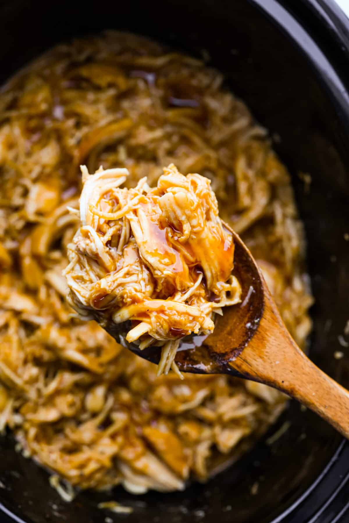 Slow cooker shredded BBQ chicken is a simple, zesty, and flavorful chicken. It can go in pasta dishes, over potatoes, in sandwiches, or in tortillas. This recipe is extremely versatile, tasty, and perfect for any time of year! Close up shot of slow cooker shredded BBQ chicken.