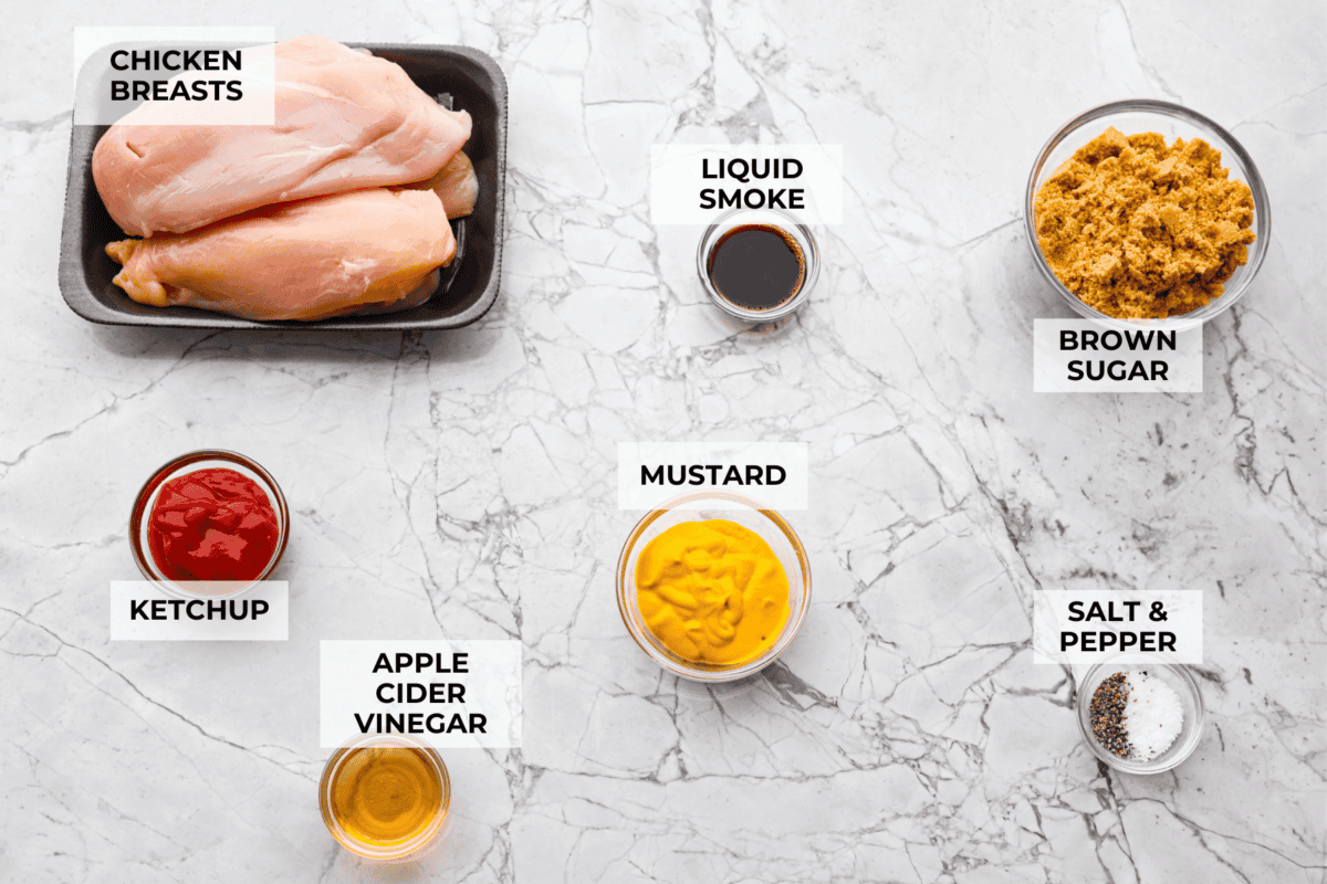 Slow cooker shredded BBQ chicken is a simple, zesty, and flavorful chicken. It can go in pasta dishes, over potatoes, in sandwiches, or in tortillas. This recipe is extremely versatile, tasty, and perfect for any time of year! Overhead shot of labeled ingredients.