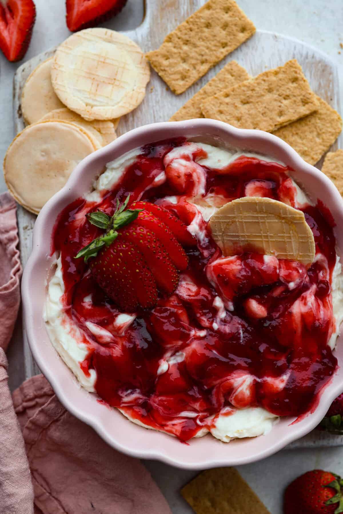 Strawberry cheesecake dip is an irresistible treat that tastes just like the classic but in a fun dip form! Whip it up in just 5 minutes! It's so good with graham crackers, fresh fruit, and cookies for a sweet, crowd-pleasing snack! Overhead shot of strawberry cheesecake dip.