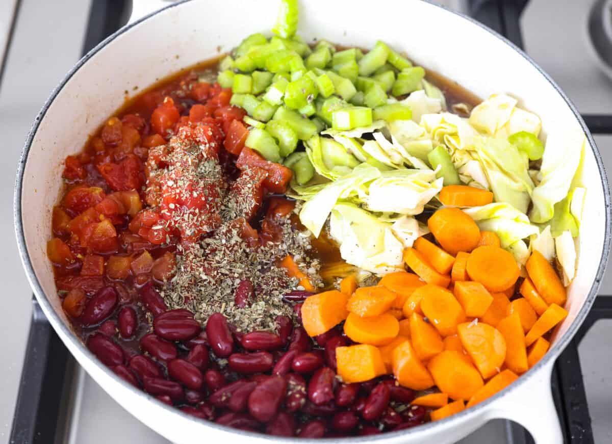 Beef and Cabbage soup is filled with seasoned ground beef, cabbage, carrots, celery, kidney beans, and diced tomatoes. It is hearty, delicious, and full of flavor! This is a great soup to serve on a cold day or to help you get in the spirit of St. Patrick's Day while keeping your nutrition goals in check. Overhead shot of the vegetables, broth, beans and seasonings added to the pot.