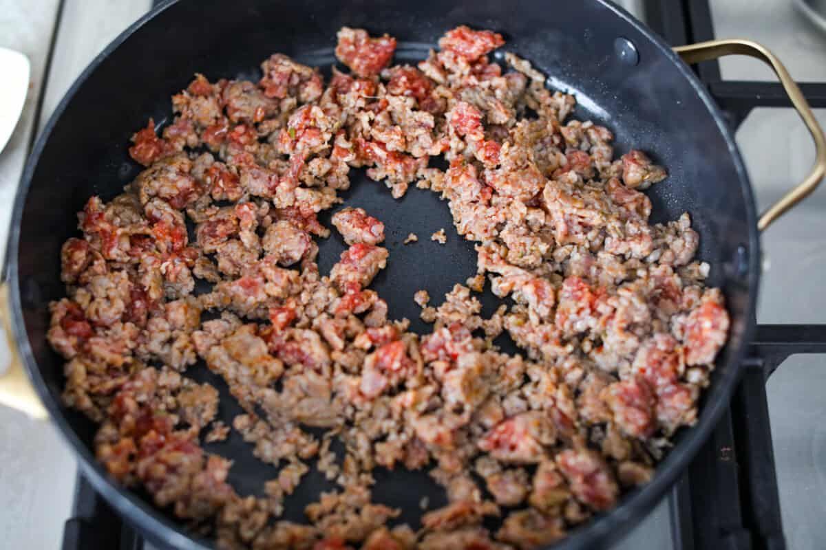 Baked spaghetti is the ultimate comfort food, with noodles that soak up all of the rich sauce as they finish cooking, making every bite extra flavorful. Plus, it’s a lifesaver on busy days. You can prep it ahead, pop it in the oven, and still have a cozy, home-cooked meal without the stress! Italian sausage cooking in a skillet.