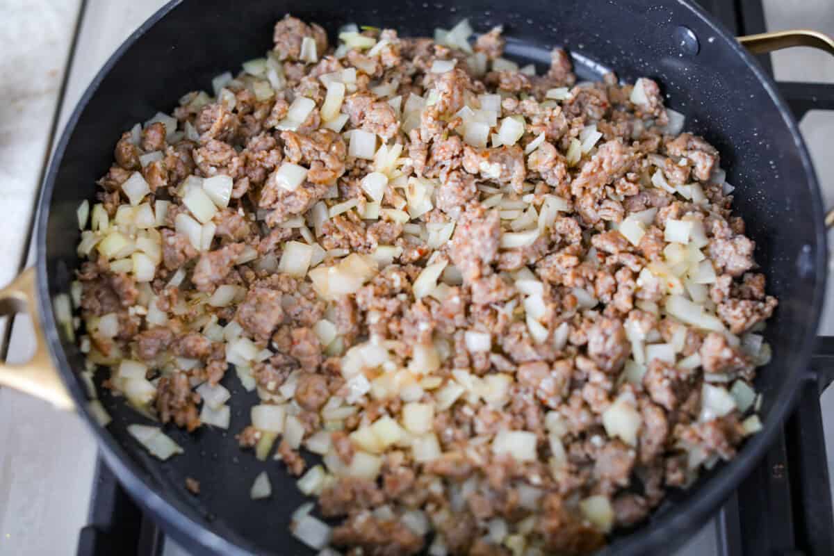 Baked spaghetti is the ultimate comfort food, with noodles that soak up all of the rich sauce as they finish cooking, making every bite extra flavorful. Plus, it’s a lifesaver on busy days. You can prep it ahead, pop it in the oven, and still have a cozy, home-cooked meal without the stress! Onions and garlic cooking with the Italian sausage.