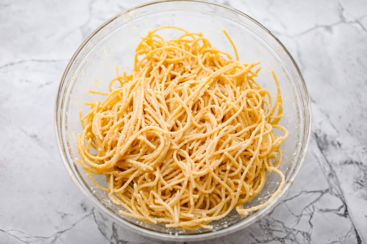 Baked spaghetti is the ultimate comfort food, with noodles that soak up all of the rich sauce as they finish cooking, making every bite extra flavorful. Plus, it’s a lifesaver on busy days. You can prep it ahead, pop it in the oven, and still have a cozy, home-cooked meal without the stress! Overhead shot of noodles mixed with the egg, butter and cheese mixture.