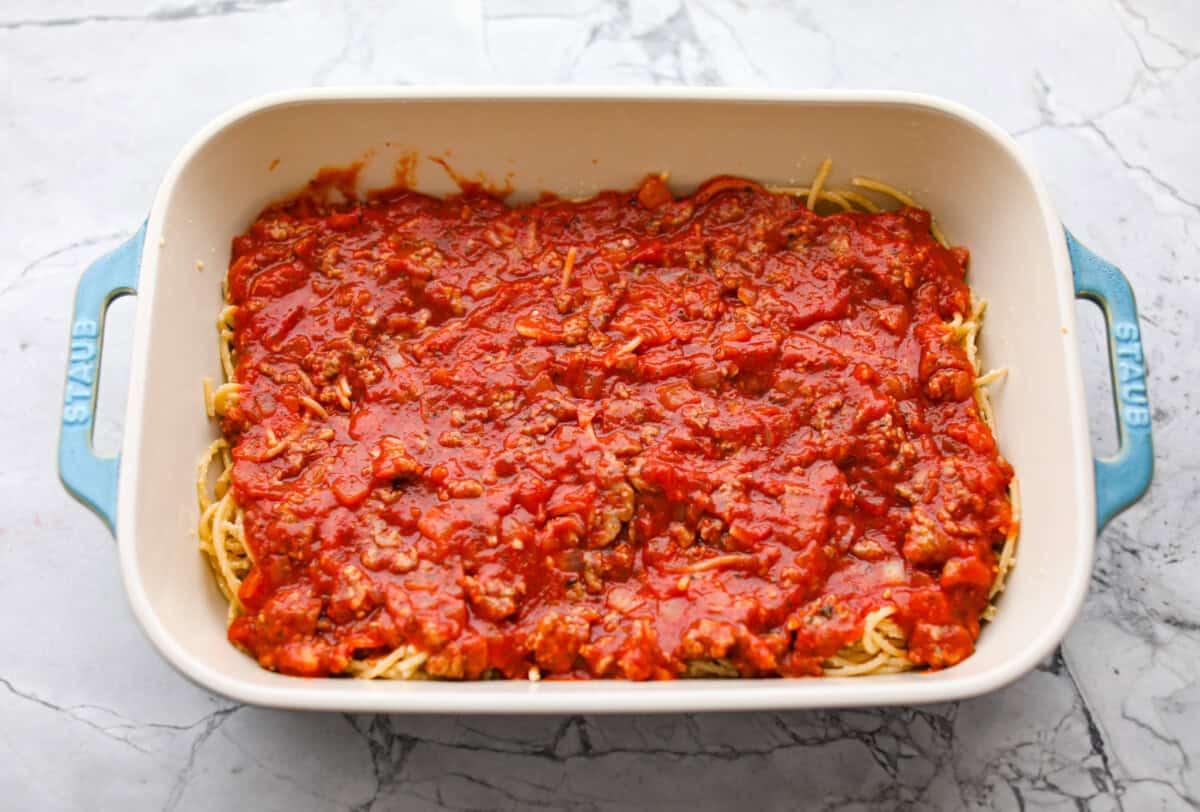 Baked spaghetti is the ultimate comfort food, with noodles that soak up all of the rich sauce as they finish cooking, making every bite extra flavorful. Plus, it’s a lifesaver on busy days. You can prep it ahead, pop it in the oven, and still have a cozy, home-cooked meal without the stress! Meat sauce layered on top of the noodles in the baking dish.