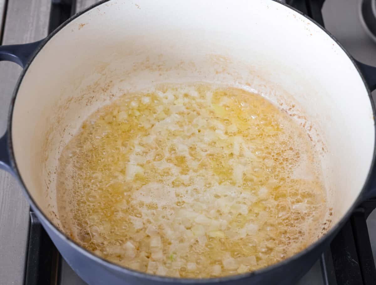 This colcannon soup is a creamy, luscious soup inspired by the traditional Irish dish that is made with potatoes, cabbage, kale, butter, and cream. This would be a great recipe to start a St. Patrick's Day tradition with your family. Angle shot of onions sautéing in butter.