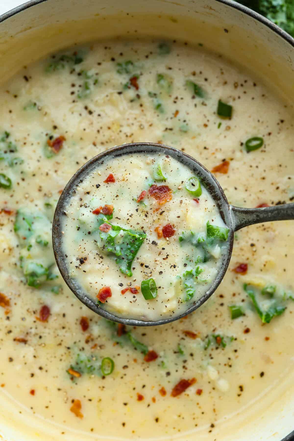This colcannon soup is a creamy, luscious soup inspired by the traditional Irish dish that is made with potatoes, cabbage, kale, butter, and cream. This would be a great recipe to start a St. Patrick's Day tradition with your family. Close up shot of a ladle filled with colcannon soup.