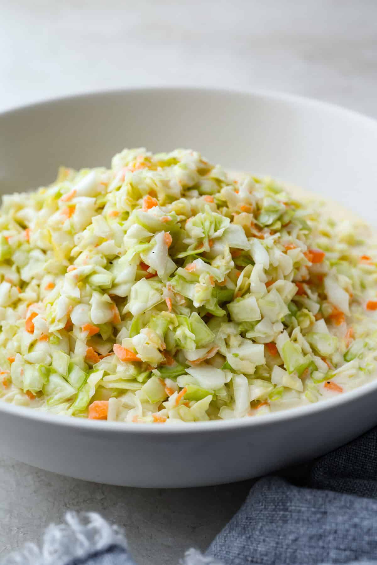 My Copycat KFC Coleslaw is so spot-on, you’ll think it’s the real deal! Crunchy, creamy, tangy, and perfect for any BBQ, everyone will want the recipe! Angle shot of copycat KFC coleslaw in a serving dish.