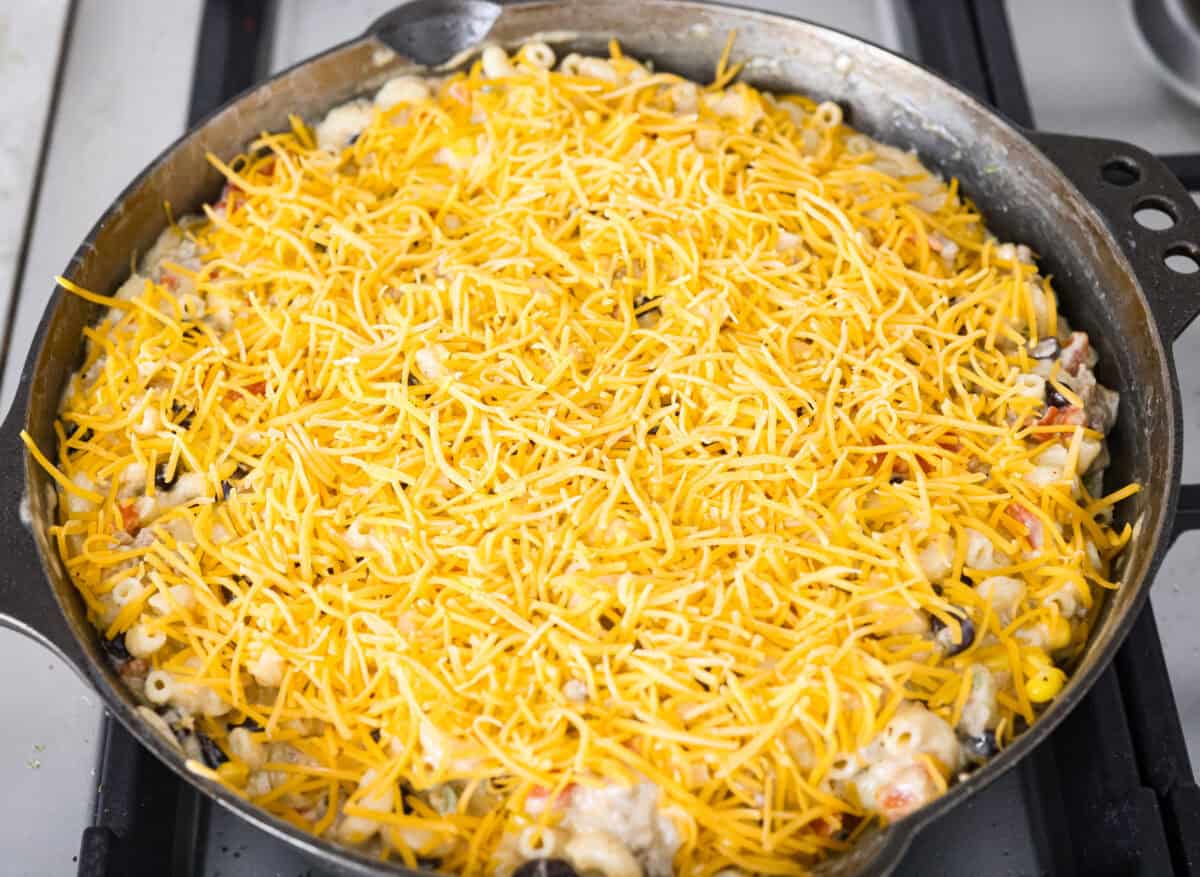 Creamy, cheesy Cowboy Mac and Cheese gets a bold twist with hearty additions like seasoned meat, tomatoes, jalapeños, corn, beans, and onions. It's rich, flavorful, and just the right amount of spice! The heat is warm but not overwhelming. If you like it spicy, add more jalapeños! Everything is stirred together in a skillet and topped with shredded cheddar cheese.