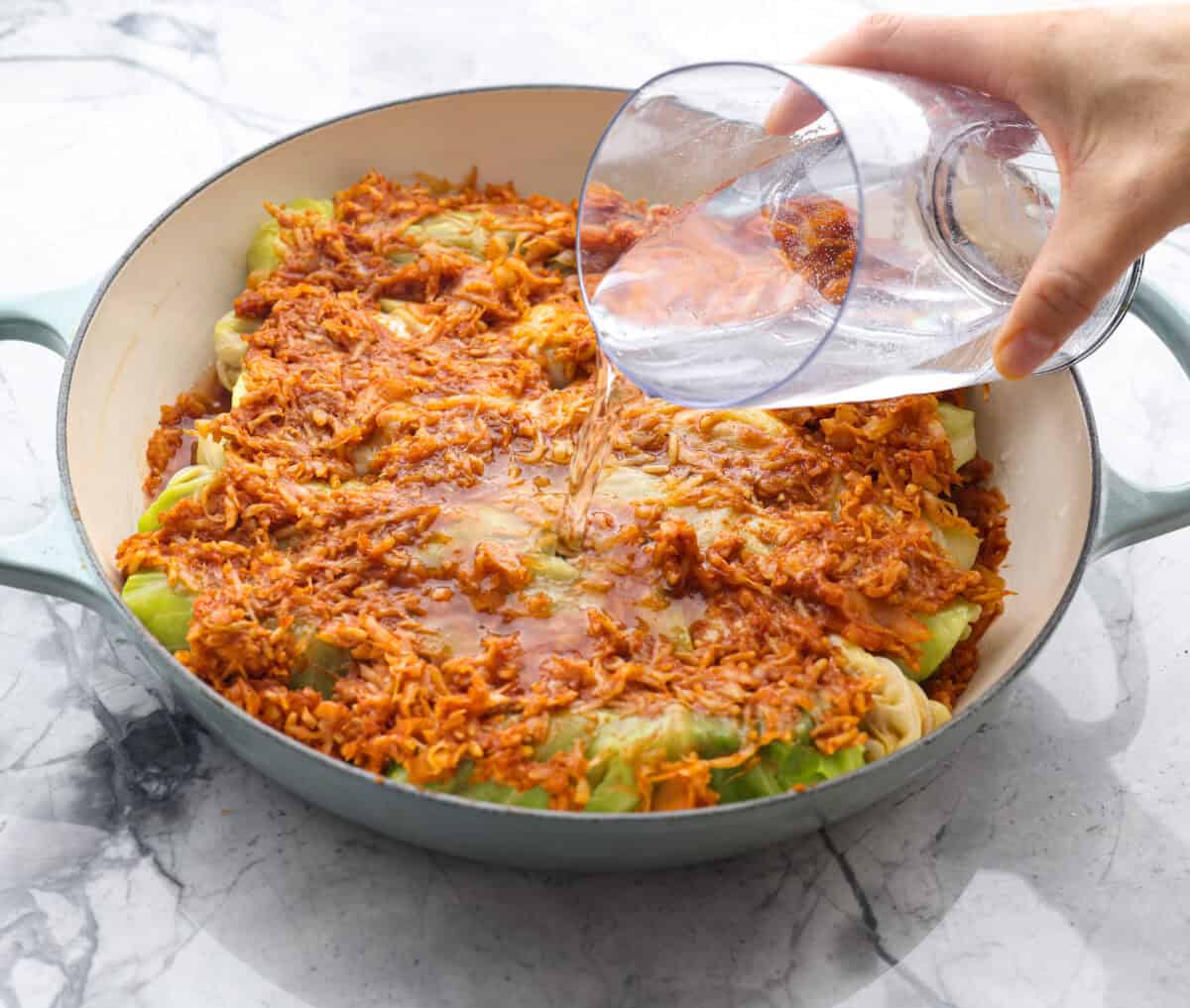 Hungarian cabbage rolls are packed with rich, hearty flavors in every bite! I know you love a good cabbage roll and can’t get enough of my Hungarian goulash, so I knew this recipe would be perfect. Angle shot of someone pouring the water into the dutch oven over the Hungarian Cabbage rolls.