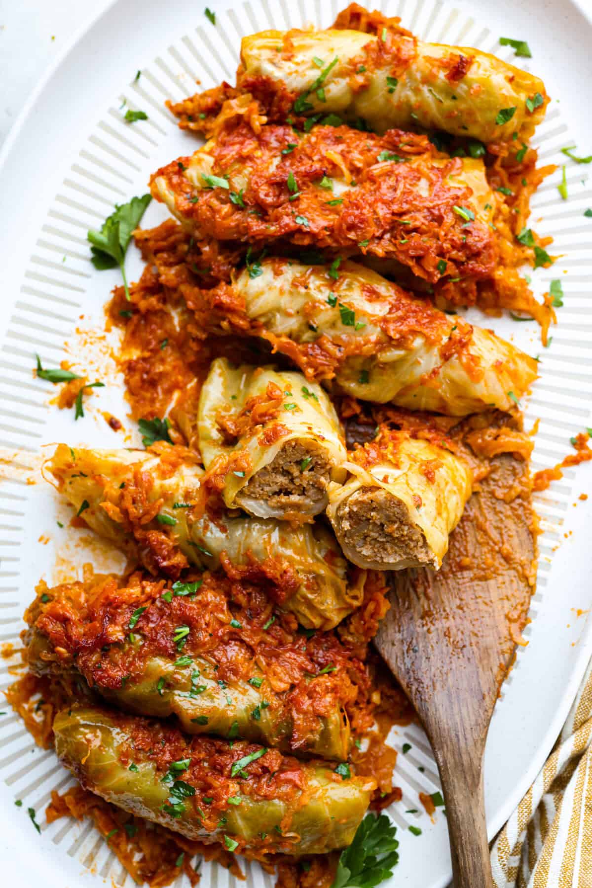 Hungarian cabbage rolls are packed with rich, hearty flavors in every bite! I know you love a good cabbage roll and can’t get enough of my Hungarian goulash, so I knew this recipe would be perfect. Overhead shot of Hungarian cabbage rolls on a platter with a wooden serving spoon.
