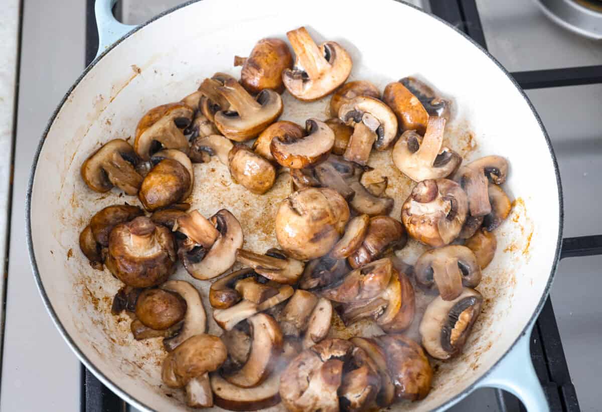 The key to making these Marry Me Mushrooms irresistibly flavorful is getting the perfect sear on the mushrooms. This locks in their natural flavors and texture. Then they simmer in a creamy garlic parmesan sauce with robust sun-dried tomatoes and herbs. It’s a simple technique that makes all the difference! Overhead shot of mushrooms cooking in butter in a skillet.