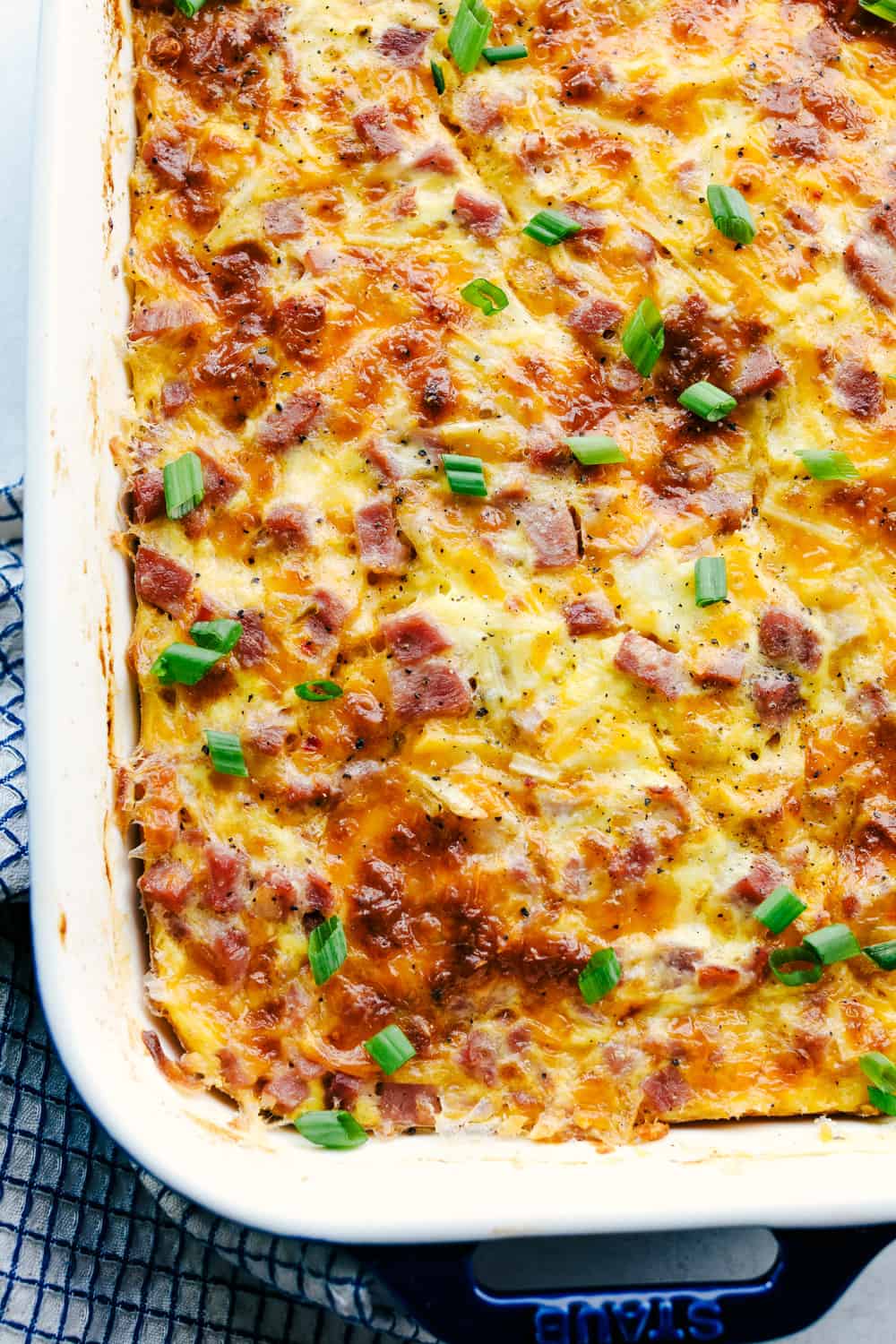 The Best Breakfast Casserole is a thick and creamy egg base with shredded potatoes, chunks of ham and flavorful cheese blends that bakes up in no time. Make ahead or enjoy the morning of during the holidays! Close up shot of baked dish.