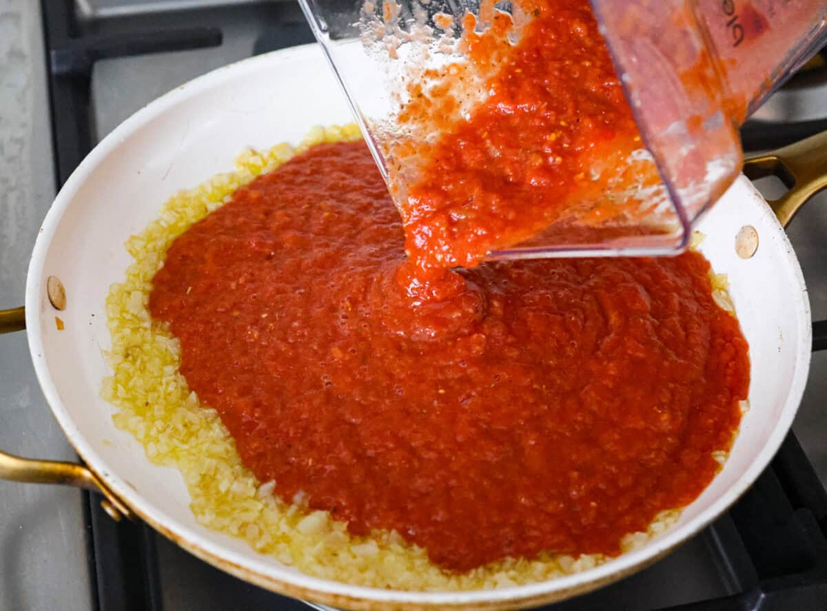 After re-testing this Homemade Marinara Sauce, I can confidently say it’s the BEST! You can make it in 15 minutes, but letting it simmer makes the flavors even better! Blended up ingredients being added to the onions in the saucepan.