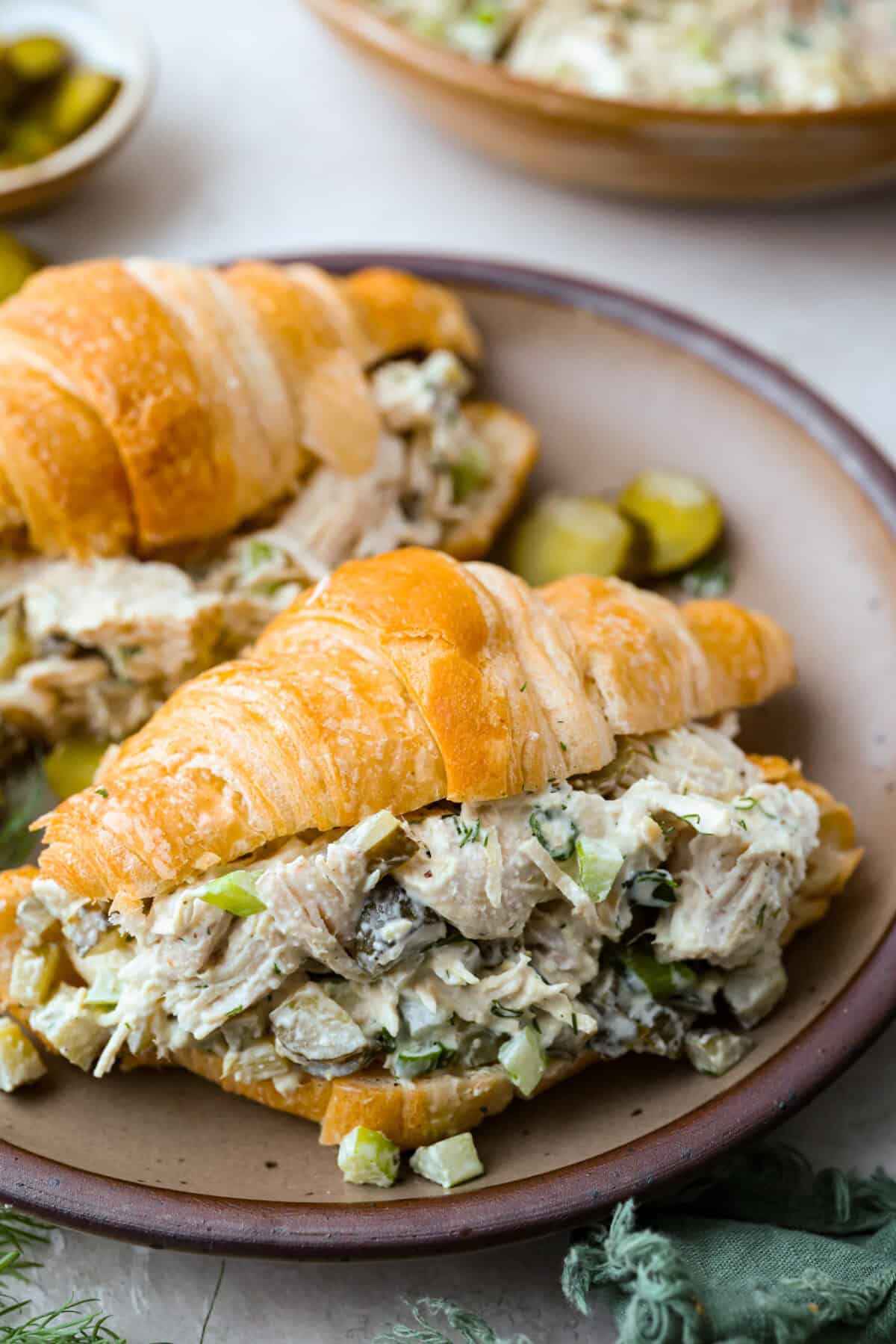Dill pickle chicken salad in a croissant on a plate.