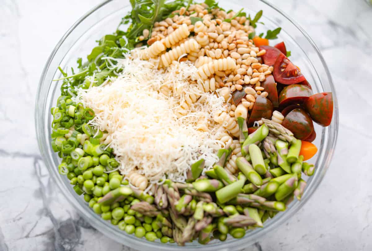 This Green Goddess Pasta Salad is fresh, vibrant, and full of flavor! The creamy herb dressing adds a tangy twist, while crisp spring veggies make it light yet hearty. Perfect for potlucks or any time you’re craving a delicious side! Process shot of all of the pasta salad ingredients in a large bowl.