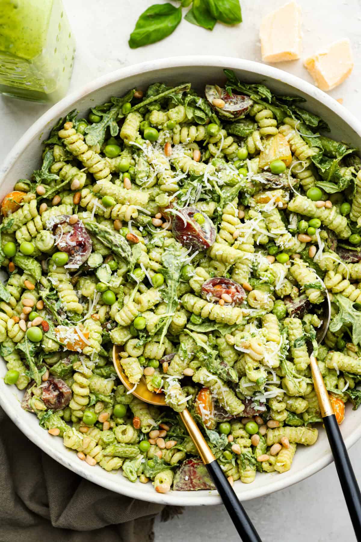 This Green Goddess Pasta Salad is fresh, vibrant, and full of flavor! The creamy herb dressing adds a tangy twist, while crisp spring veggies make it light yet hearty. Perfect for potlucks or any time you’re craving a delicious side! Overhead shot of green goddess pasta salad in a large serving dish with serving spoons.