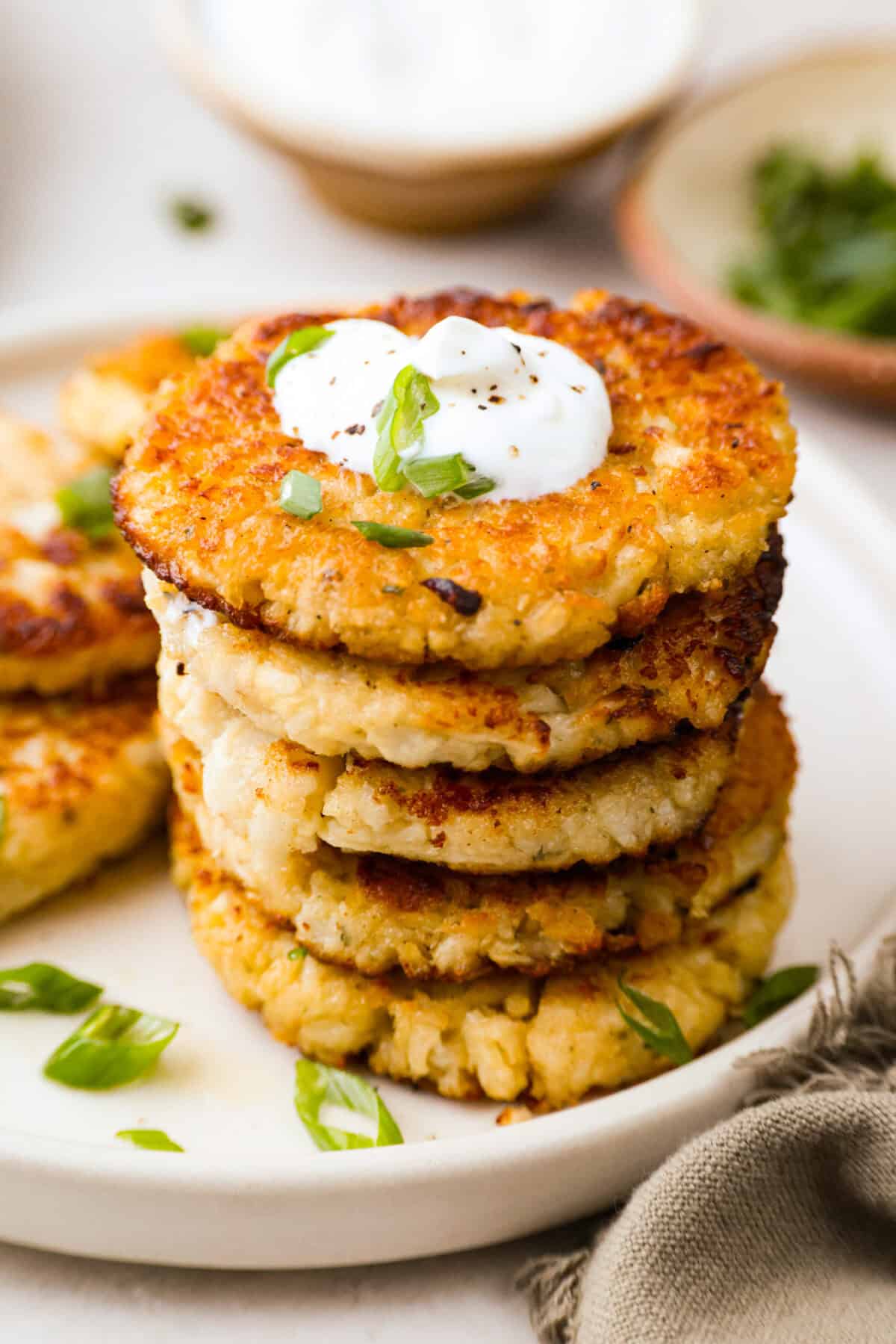 These crispy cauliflower fritters are how I trick my kids into eating veggies. They even ask for seconds. The parmesan and savory seasonings make these golden, cheesy, and packed with flavor! Stack of crispy cauliflower fritters.