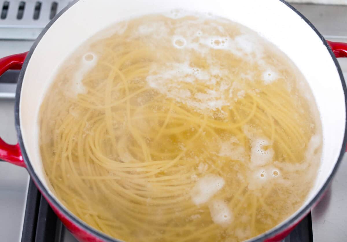 Spaghetti noodles cooking in a pot of water. 