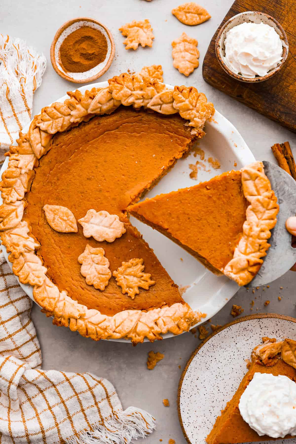 A top down view of a Thanksgiving dessert of pumpkin pie with a slice taken out of the dish. 