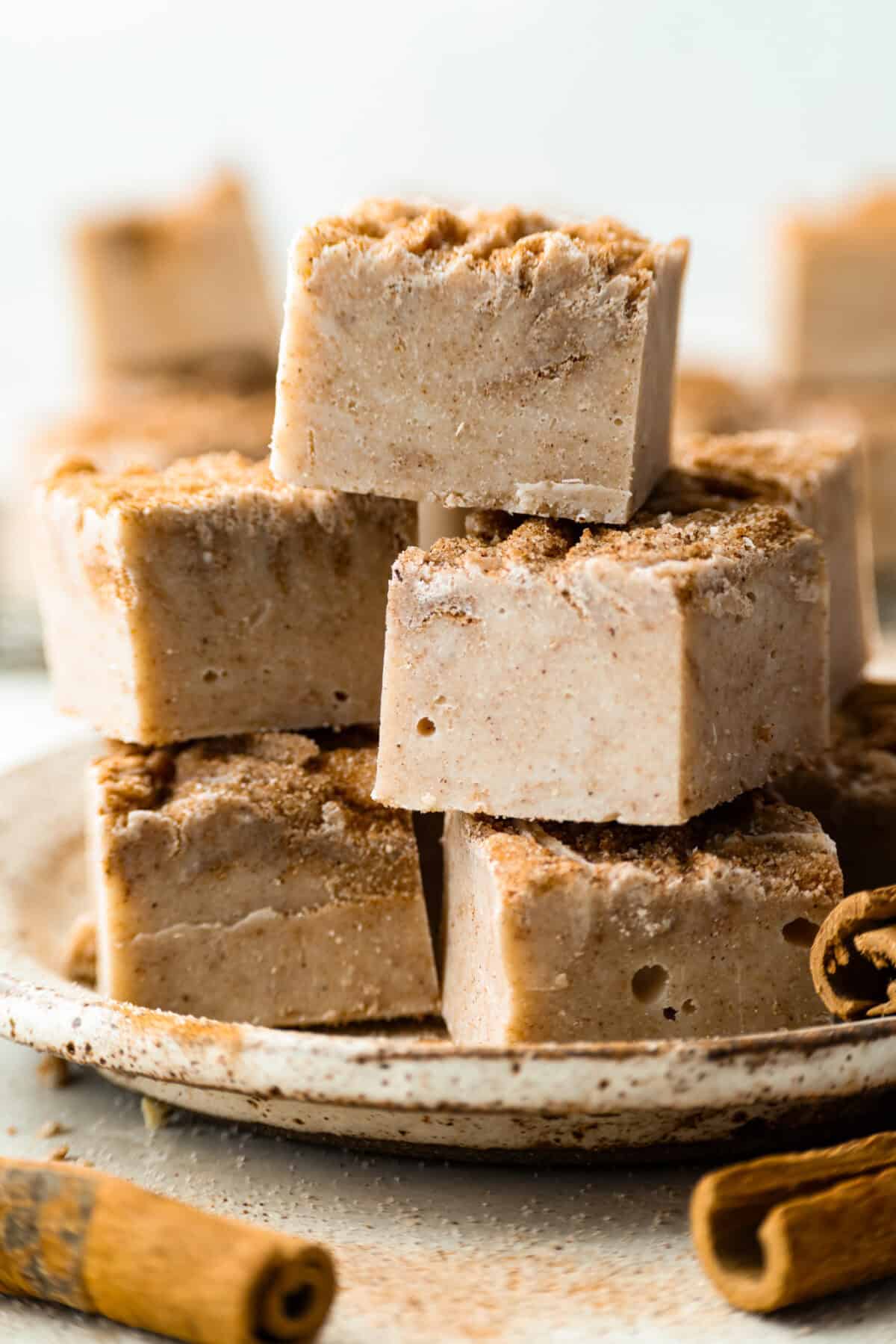 This 4-ingredient churro fudge is pure magic! It's buttery, cinnamon sugary bliss that tastes like a churro and fudge had a baby. It’s easy to make and even easier to gift (if you can resist eating it all first!). Stacked pieces of churro fudge.