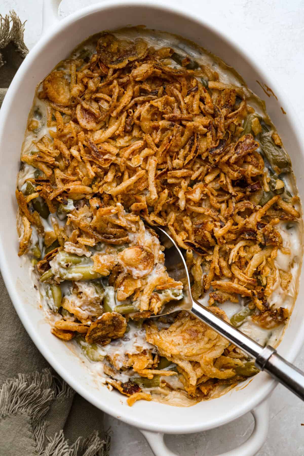 Thanksgiving doesn’t have to mean a long grocery list or an expensive spread. This 5-ingredient green bean casserole keeps things simple, affordable, and classic. It’s proof that comfort food doesn’t need a dozen ingredients. Overhead shot of baked 5 ingredient green bean casserole in the baking dish.