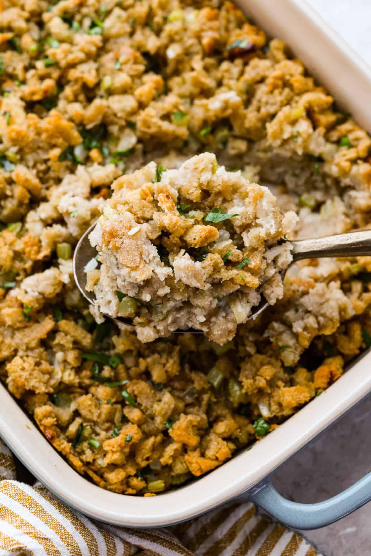 This 5-ingredient stuffing has the same buttery, herby taste as the traditional recipe. All the flavor of classic Thanksgiving stuffing on a budget! You don’t need a long ingredient list to get big holiday flavor. Someone lifting a scoop of cooked 5-ingredient stuffing out of the baking dish.