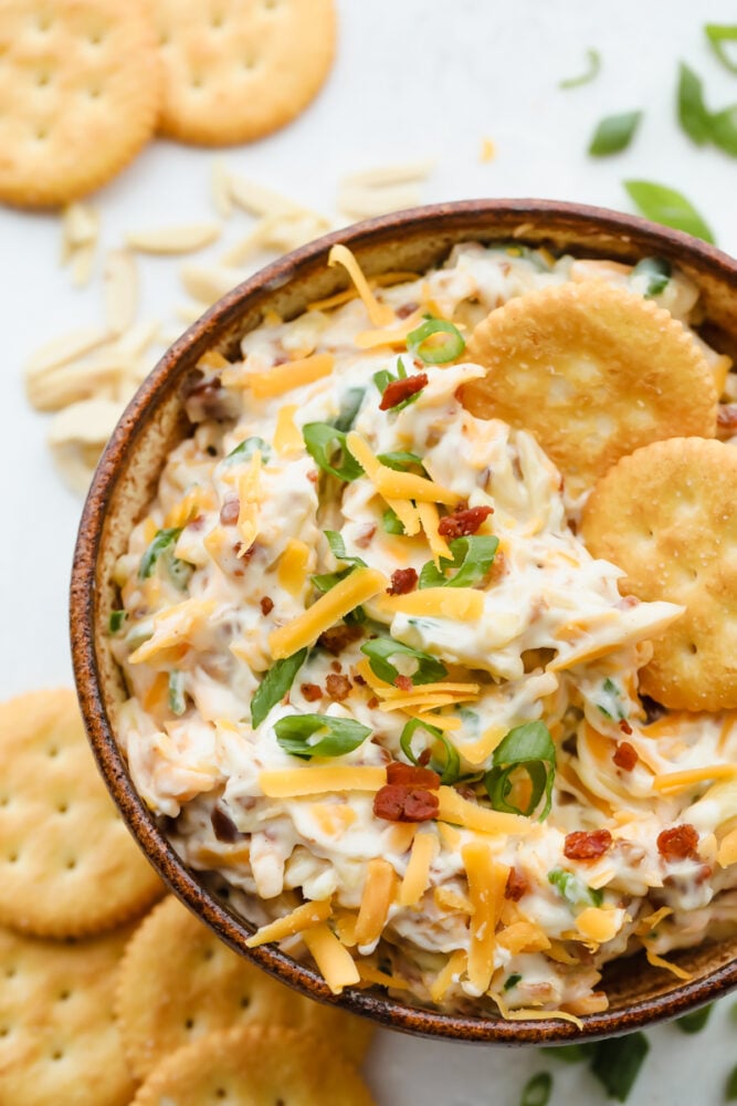 Million Dollar Dip, also known as the famous Neiman Marcus Dip, is creamy, cheesy, and loaded with almonds, green onions, and bacon. It’s the ultimate appetizer that everyone asks for the recipe. Crackers in million dollar dip.