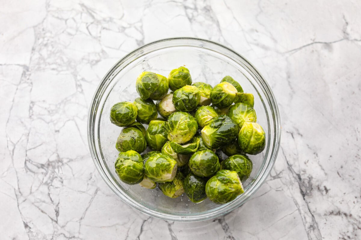 I love bacon. I love Brussels sprouts. Put them together and I’m sold. But the secret to these bacon-wrapped Brussels sprouts? A drizzle of maple syrup! It makes them sweet, smoky, and completely irresistible. Bowl of washed and trimmed Brussels sprouts.