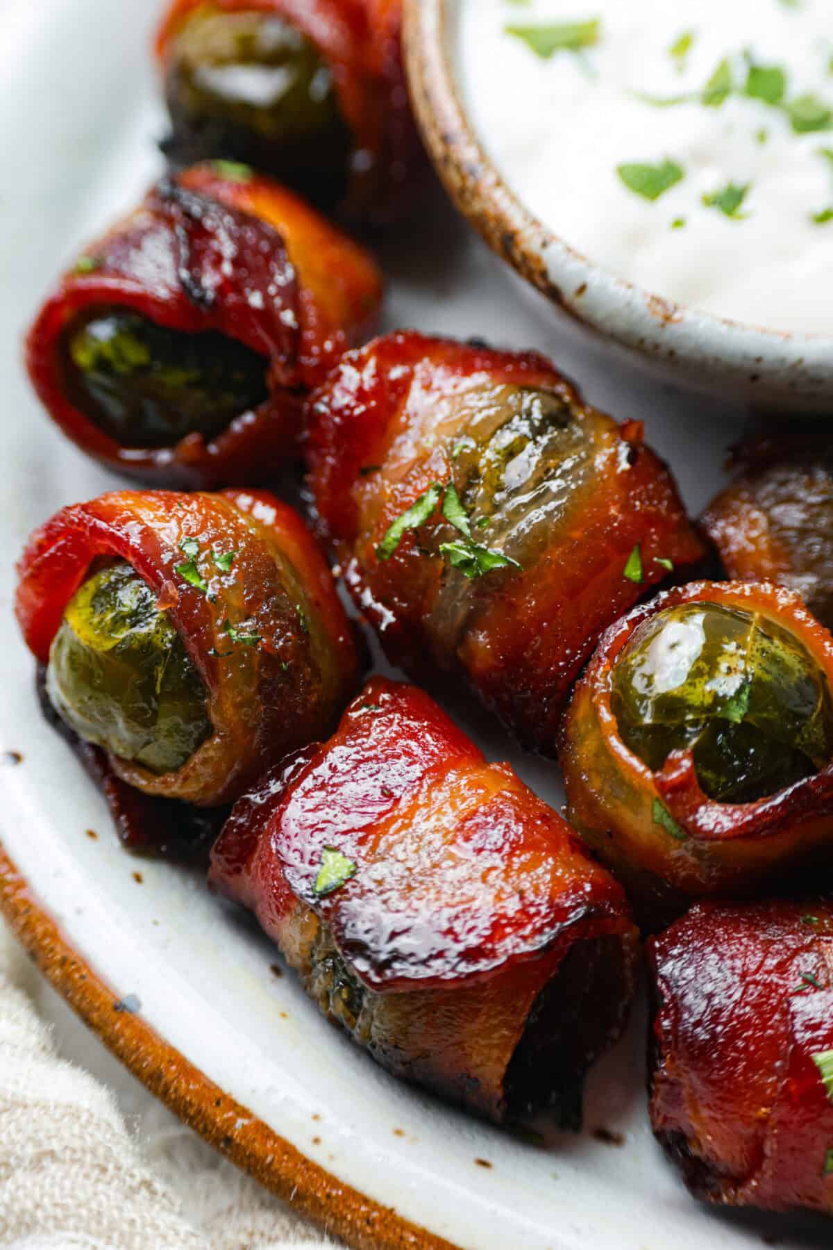 I love bacon. I love Brussels sprouts. Put them together and I’m sold. But the secret to these bacon-wrapped Brussels sprouts? A drizzle of maple syrup! It makes them sweet, smoky, and completely irresistible. Close up shot of the bacon wrapped Brussels sprouts.