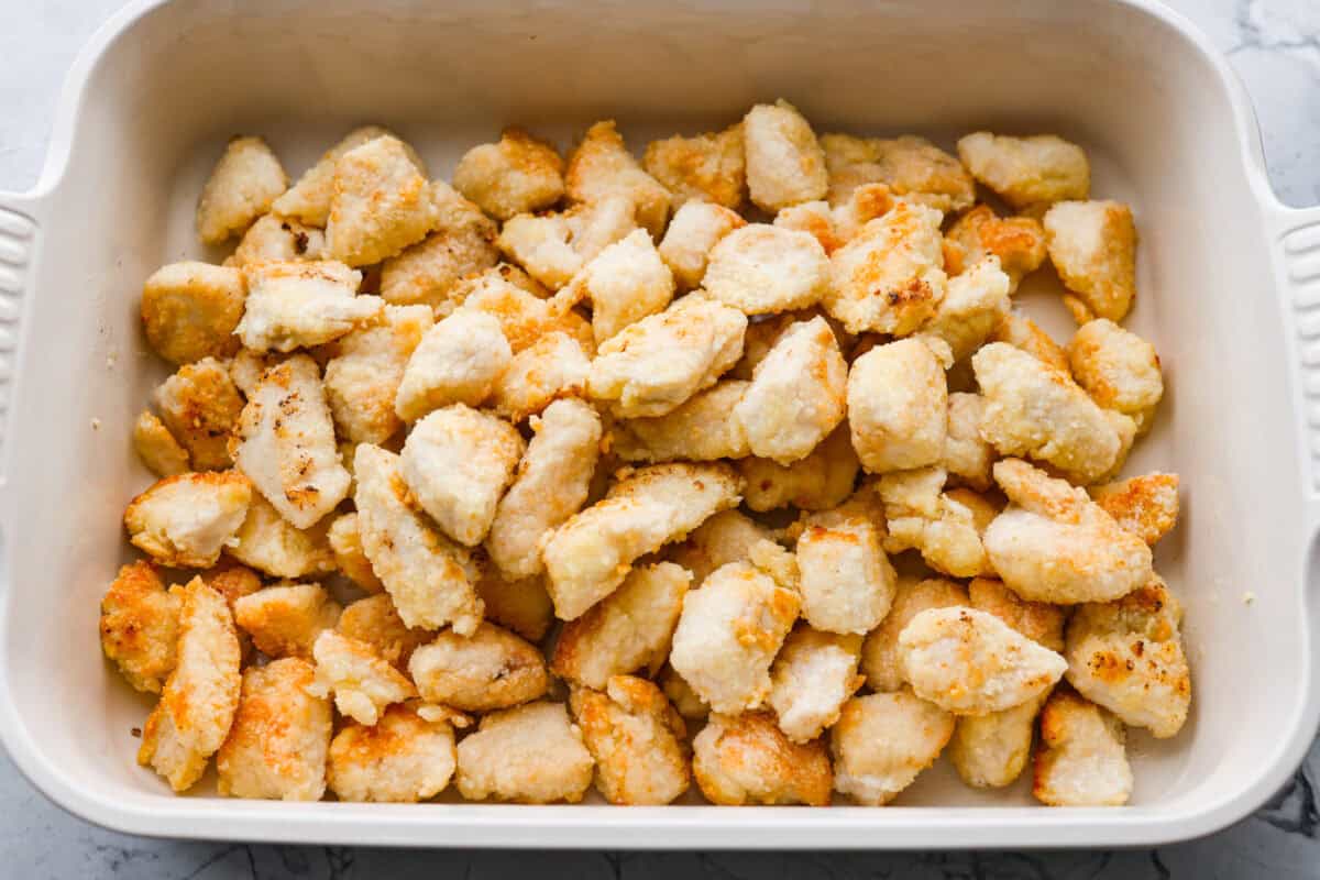 Skip the takeout and make this easy baked General Tso’s chicken at home! It’s crispy, saucy, and perfectly sweet with just the right amount of heat, no deep fryer required. Browned chicken added to a baking dish.